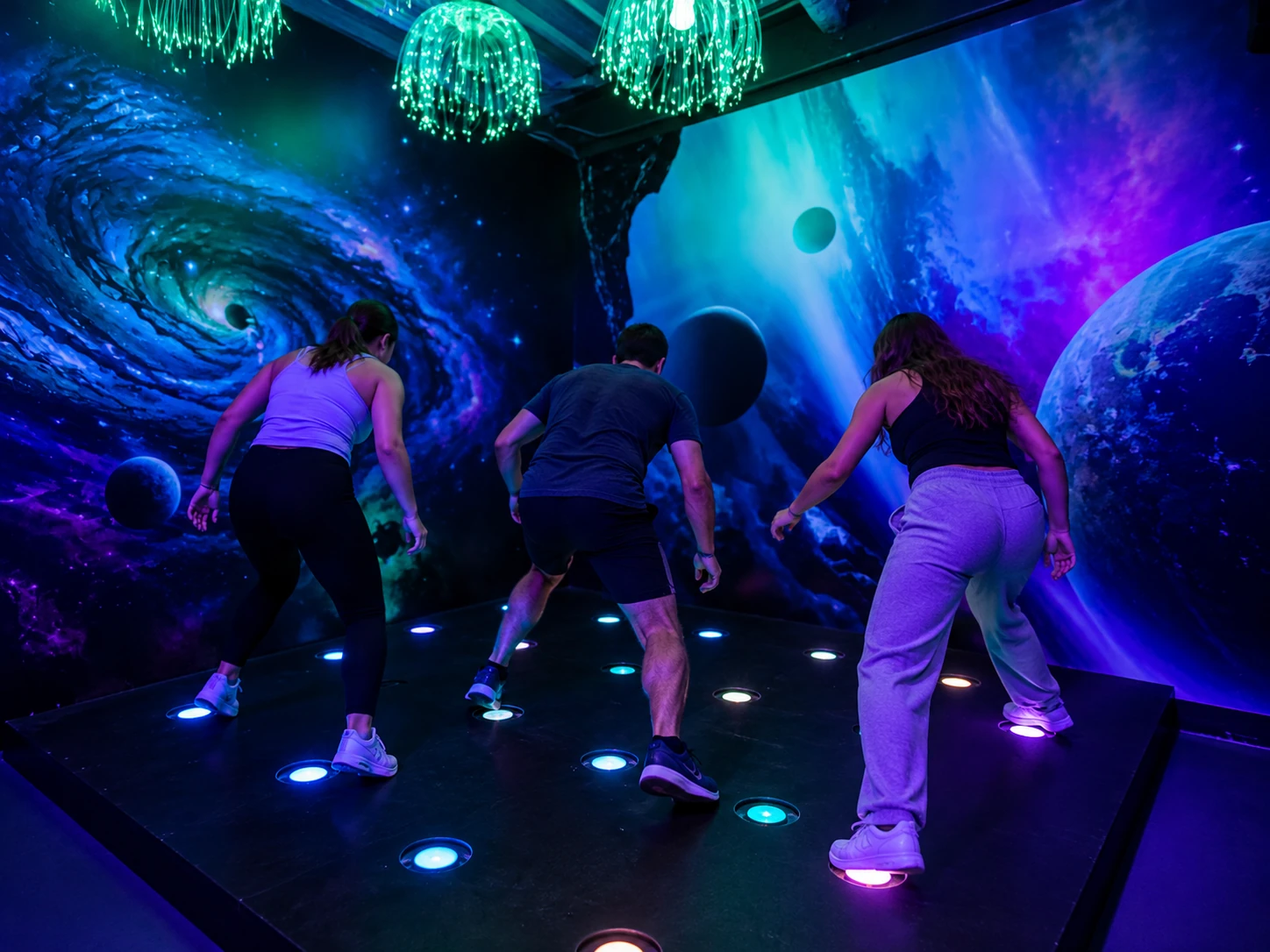 Trois joueurs de dos dans une salle immersive sur le thème de la galaxie